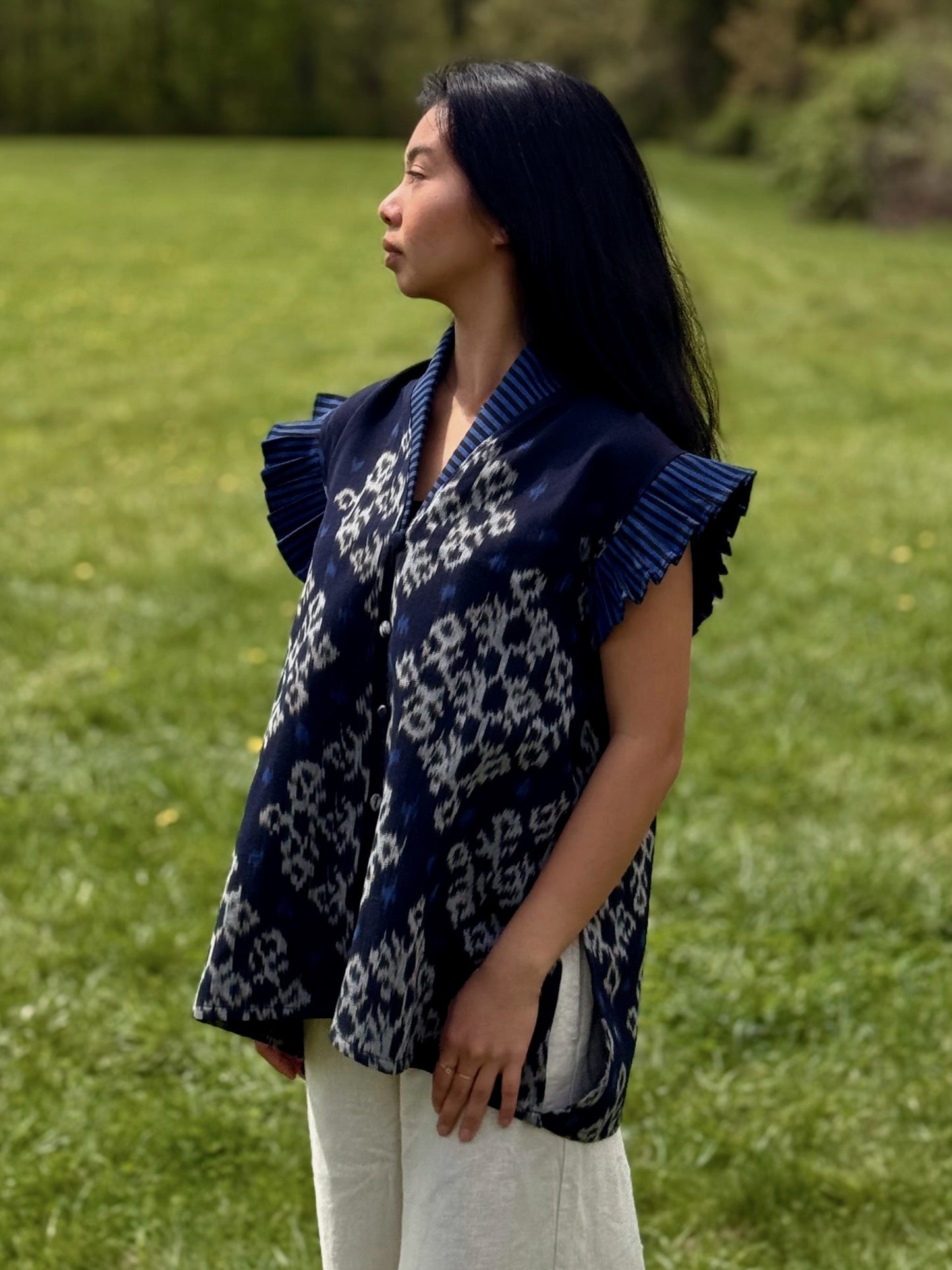 Model wearing navy Adora top with patterns and pleated sleeves standing outdoors.