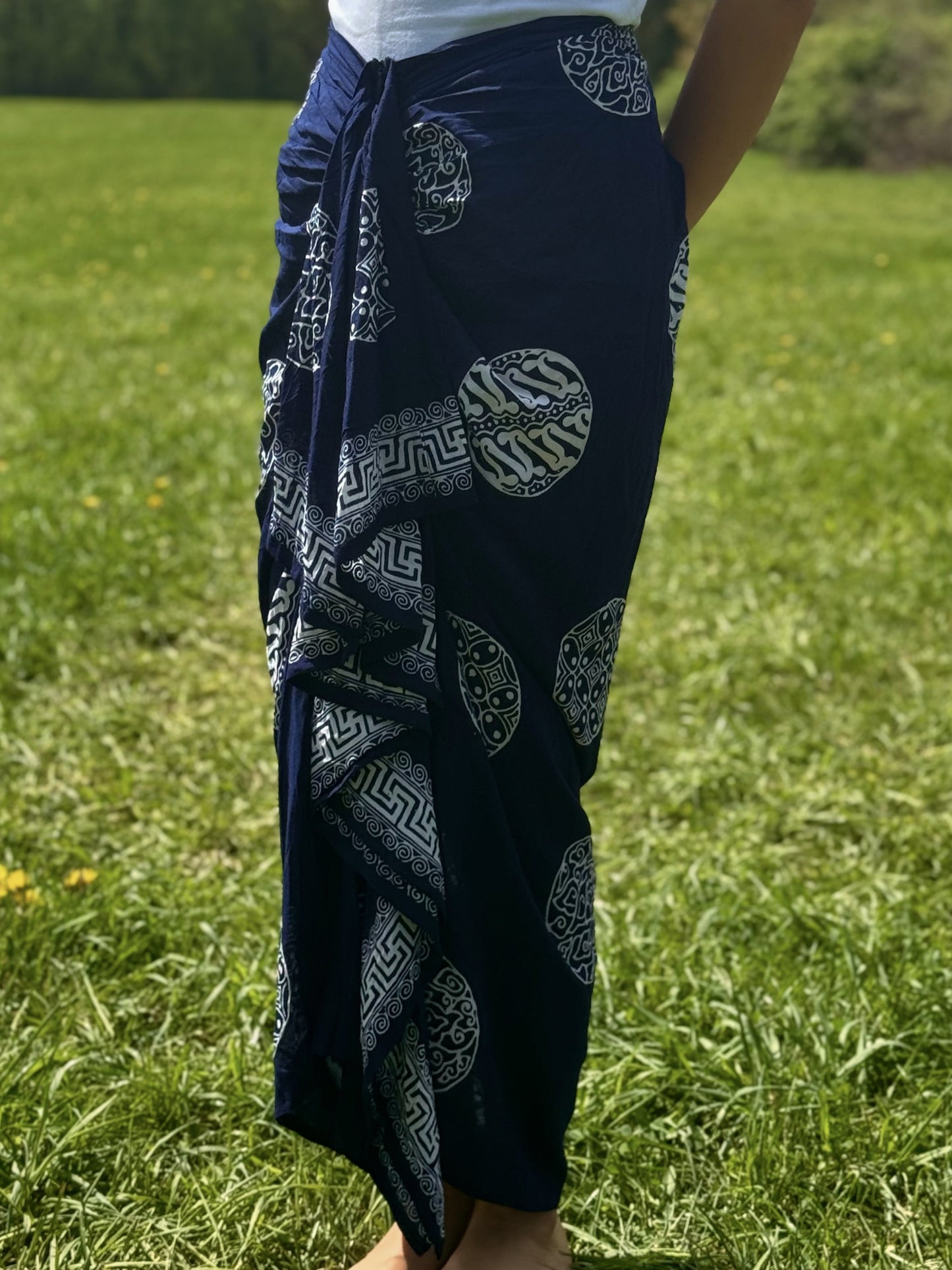 Close-up of navy sarong skirt with intricate white patterns and draped front design.