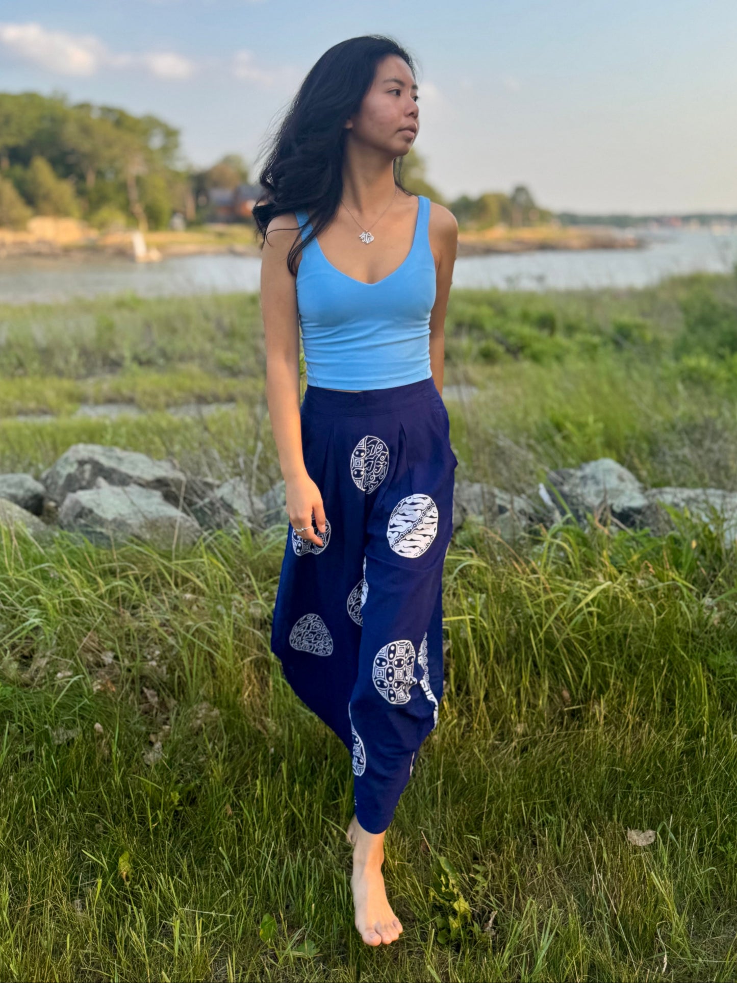 Model wearing navy Dewi Yoga pants with circle motifs in grassy field.