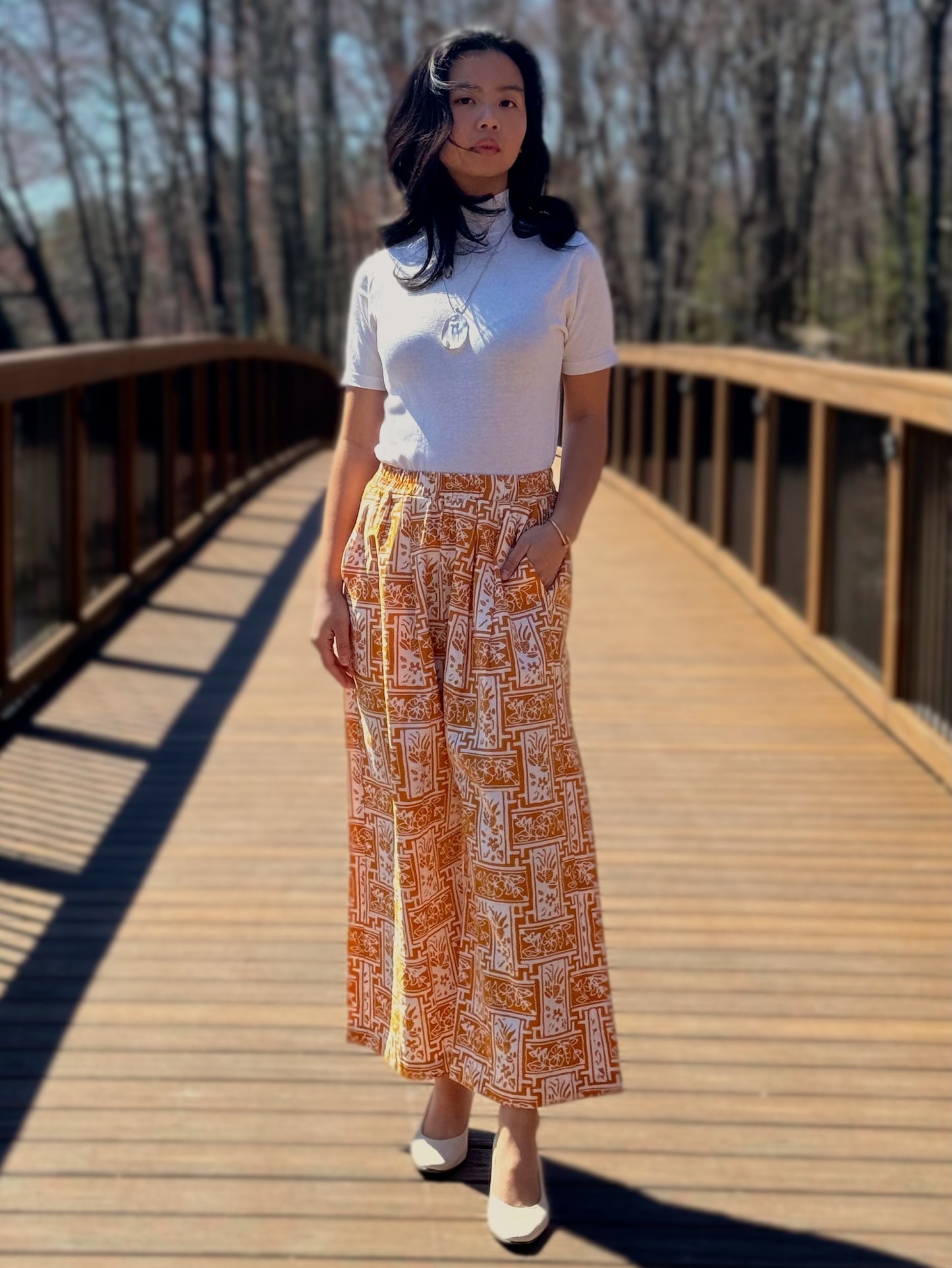 Model wearing Nami Barrel pants in Yellow, on a bridge.