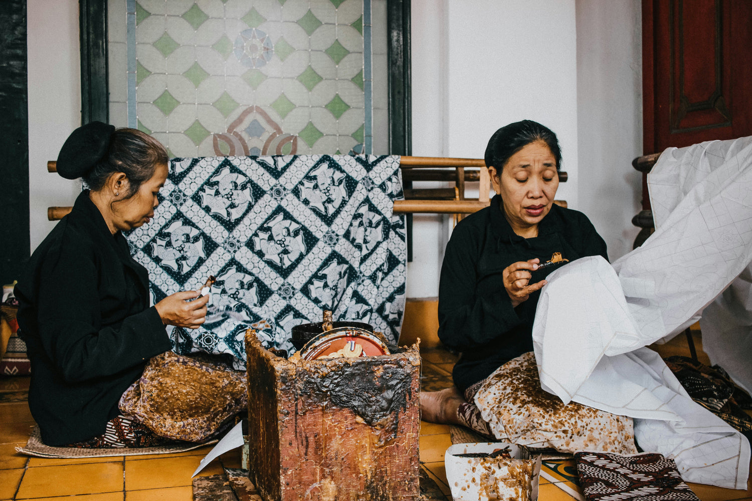 two women are drawing patterns onto a fabric.