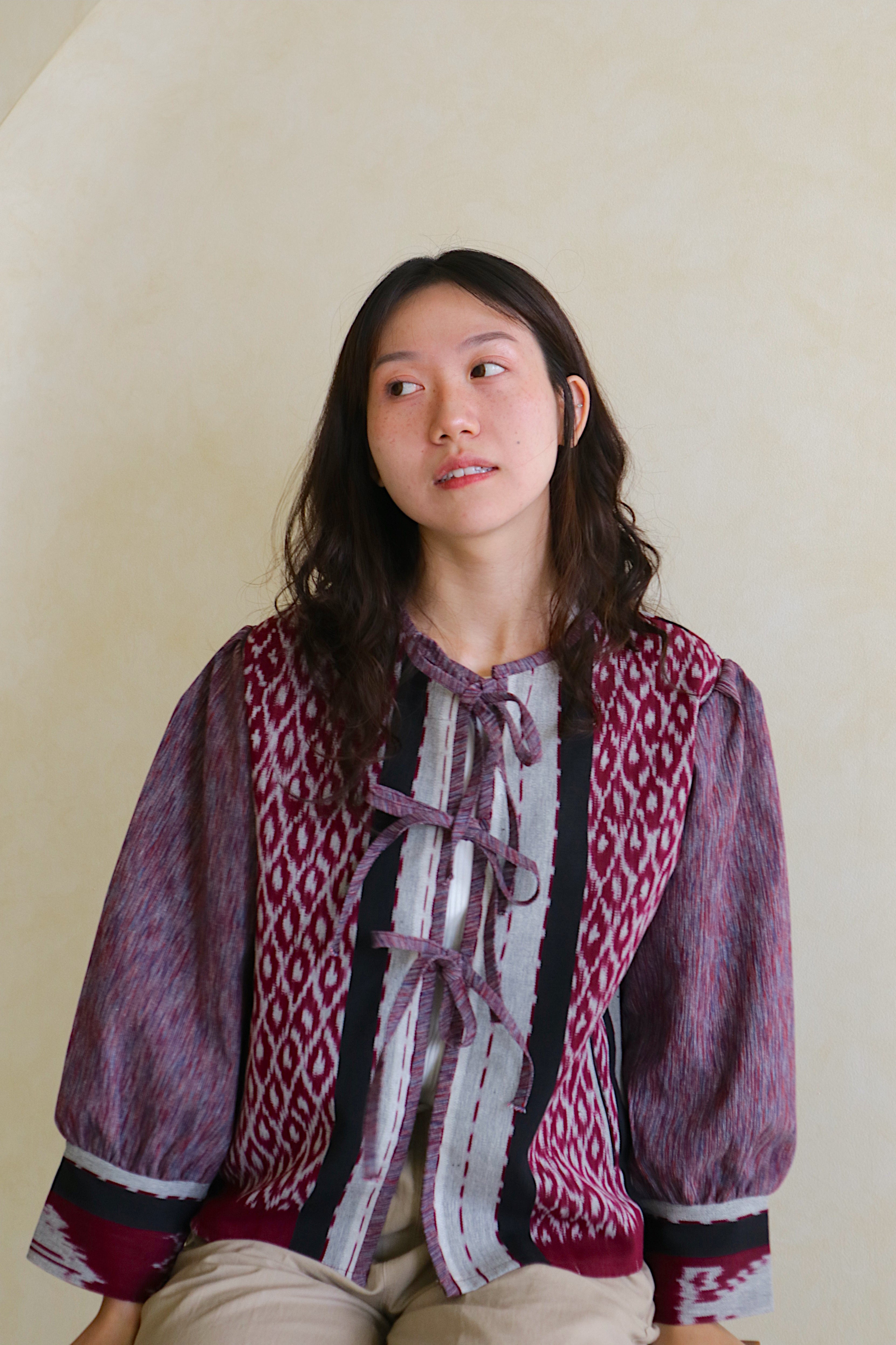 Woman wearing a patterned bow tie shirt on a plain background