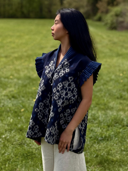Model wearing navy Adora top with patterns and pleated sleeves standing outdoors.