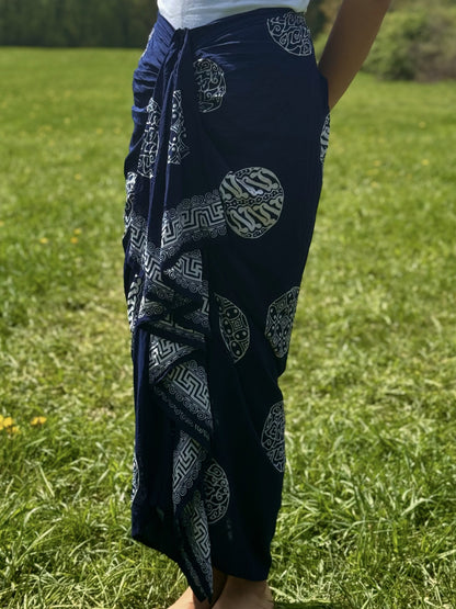 Close-up of navy sarong skirt with intricate white patterns and draped front design. 