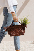 Model in casual wear carrying dark brown Nara bag by Mutiara Heritage, filled with flowers