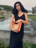 Model holding the Fitri Rattan cane bag by the ocean.