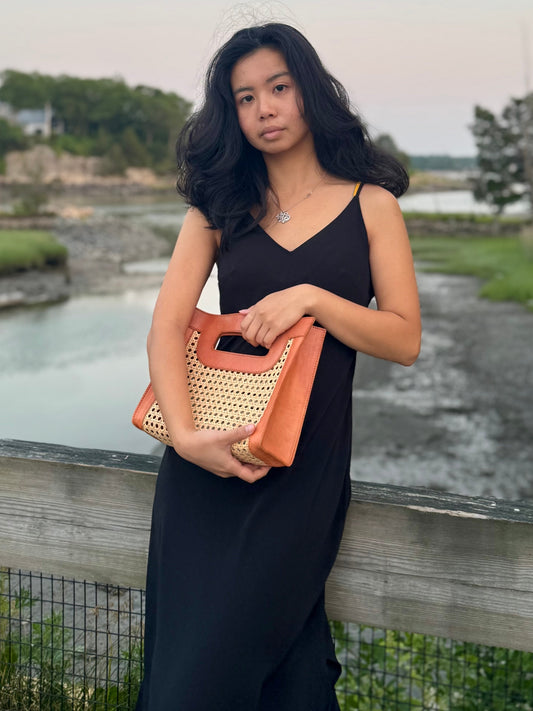 Model holding the Fitri Rattan cane bag by the ocean.