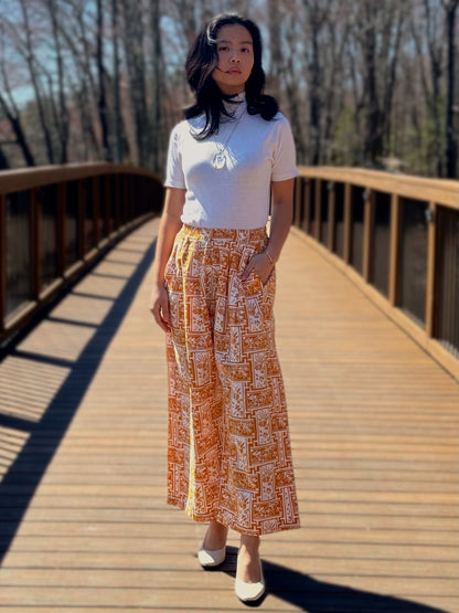 Model wearing Nami Barrel pants in Yellow, on a bridge.