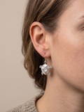 Close-up of a person wearing silver turtle-shaped earrings against a neutral background