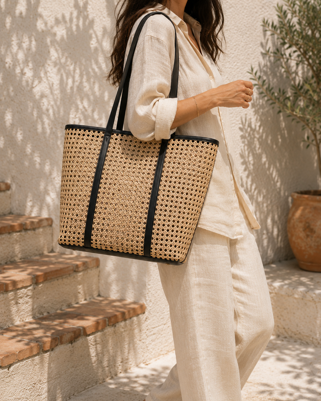 Person holding a woven tote bag outdoors on a sunny day
