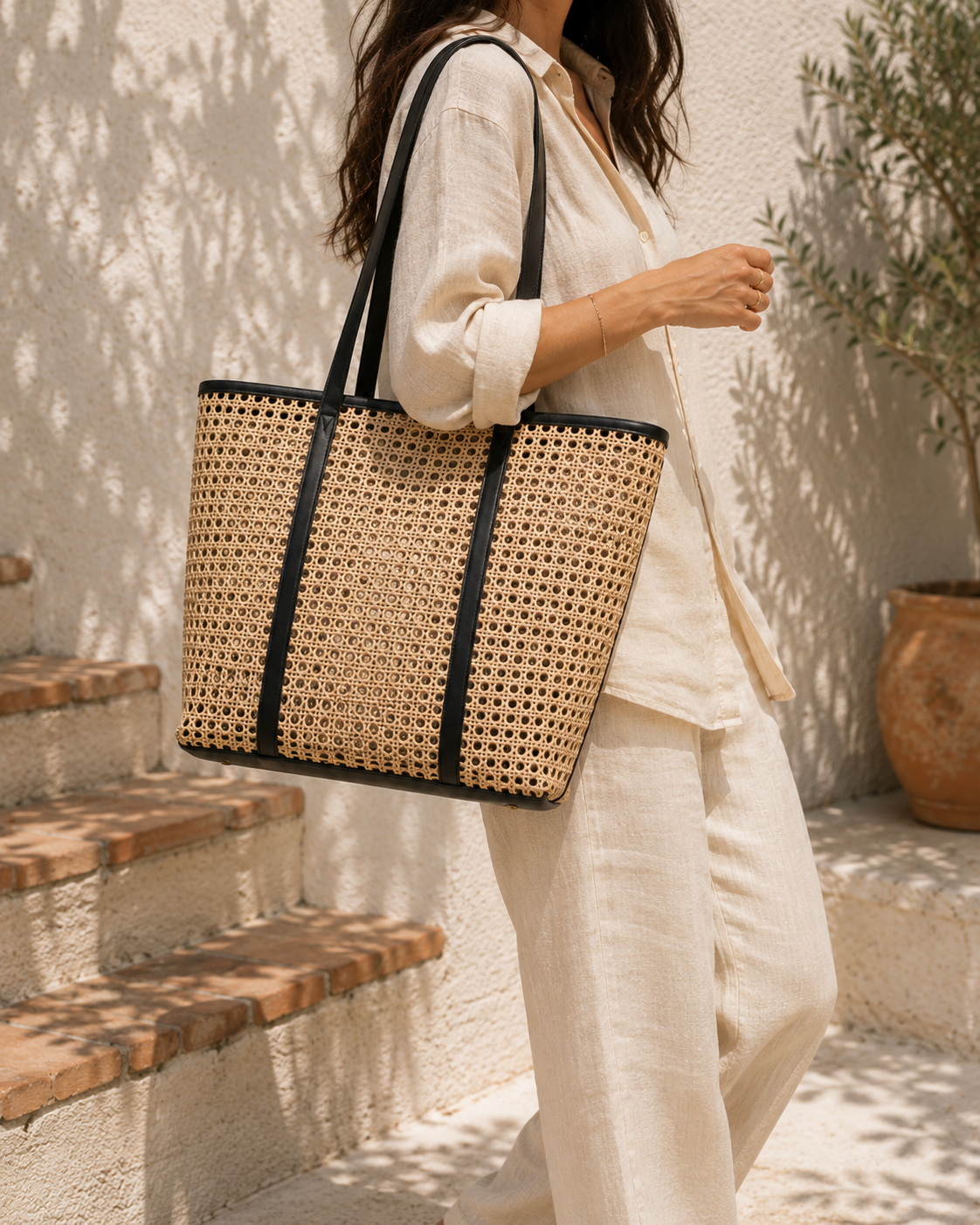 Person holding a woven tote bag outdoors on a sunny day