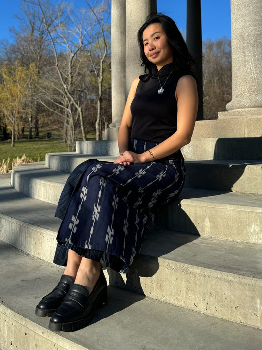 Model wearing tenun reversible skirt sitting on the stairs.