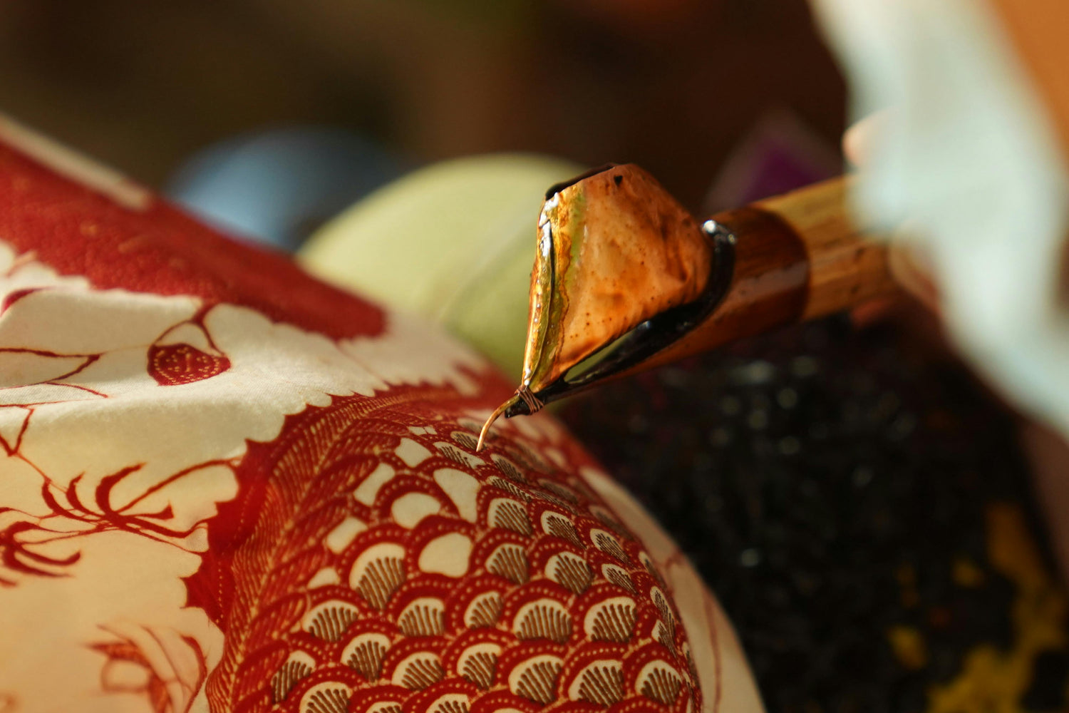 a picture of batik creation process, where wax is drawn by hand onto the fabric